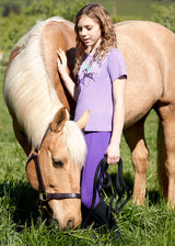 Rider standing beside a horse, wearing the tights, highlighting the blend of functionality and style for young equestrians